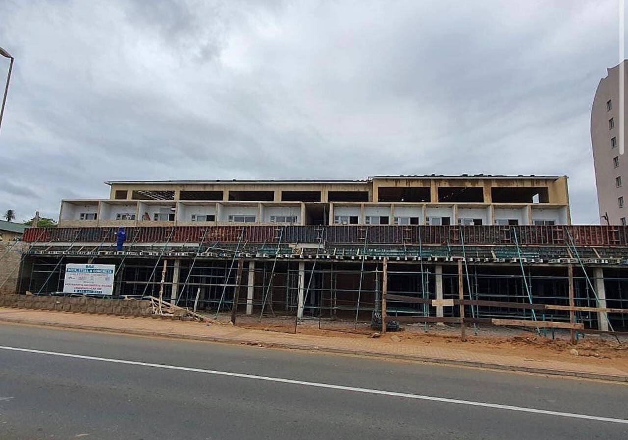 Multi-storey commercial building under construction with scaffolding along a main road