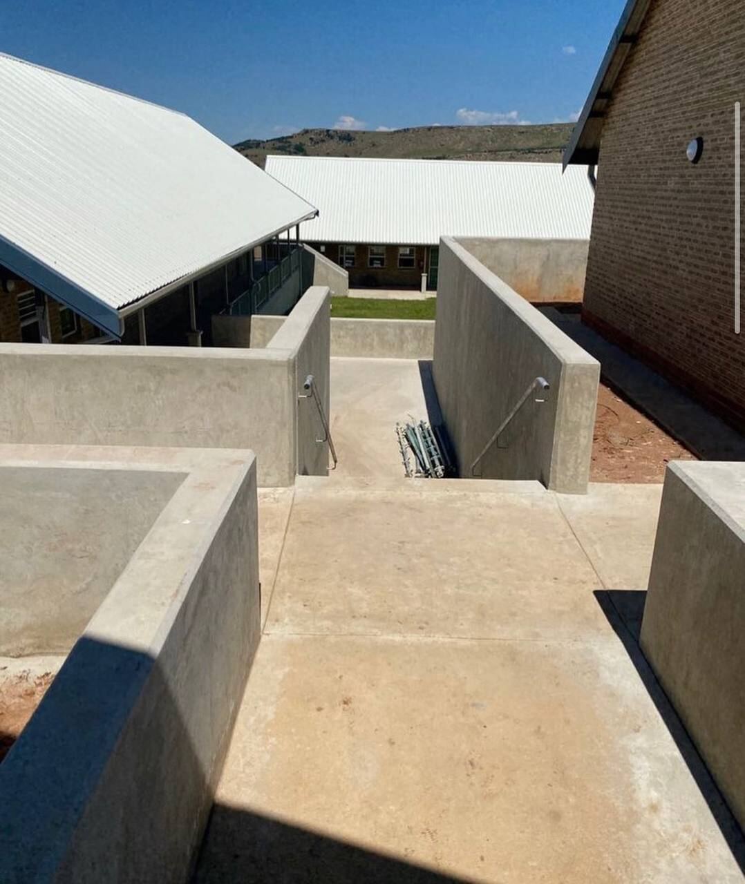 Precast concrete retaining walls and walkways connecting brick accommodation buildings on a school campus