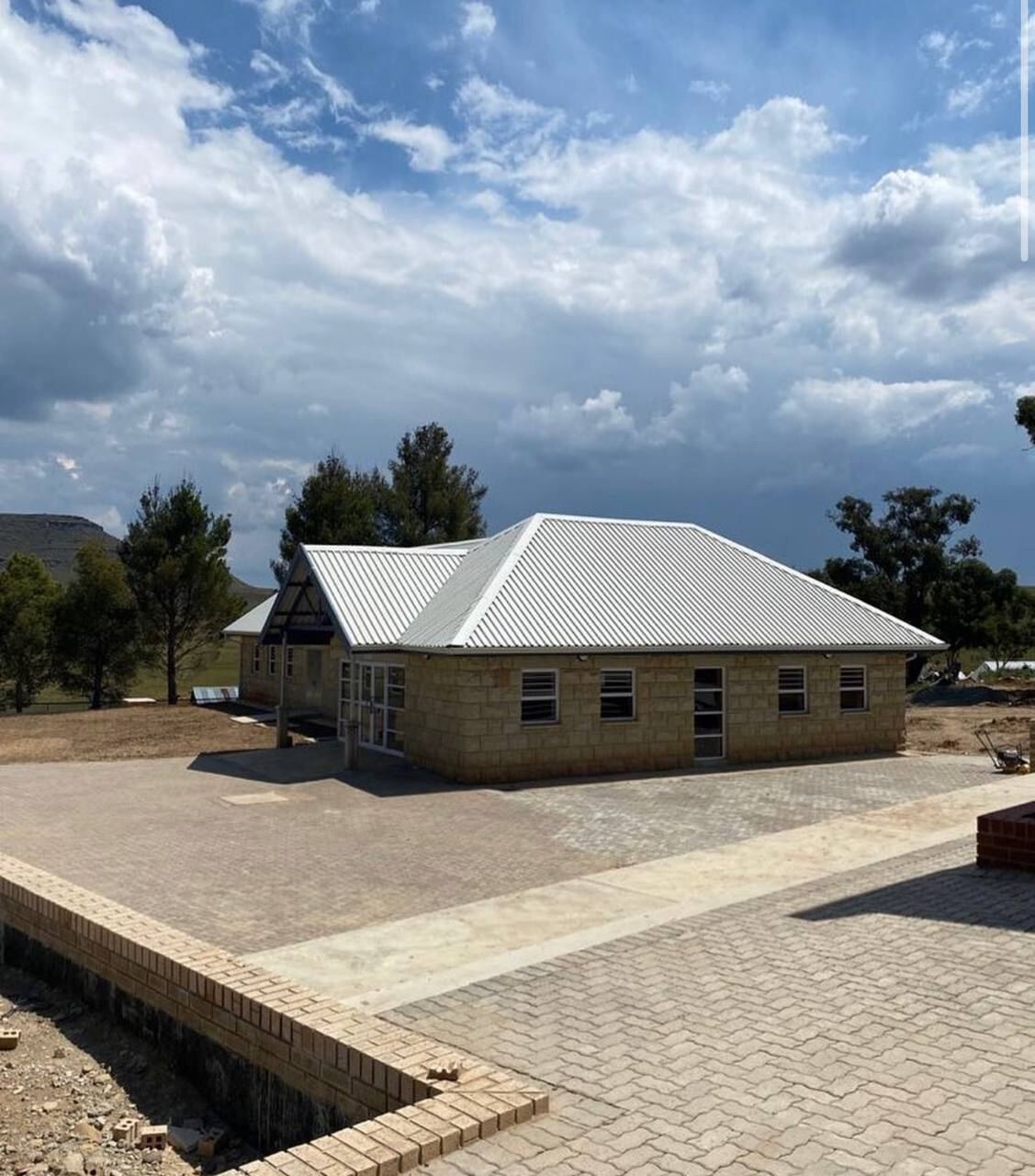 Completed single-storey brick building with new metal roof, paving and landscaping on a rural site