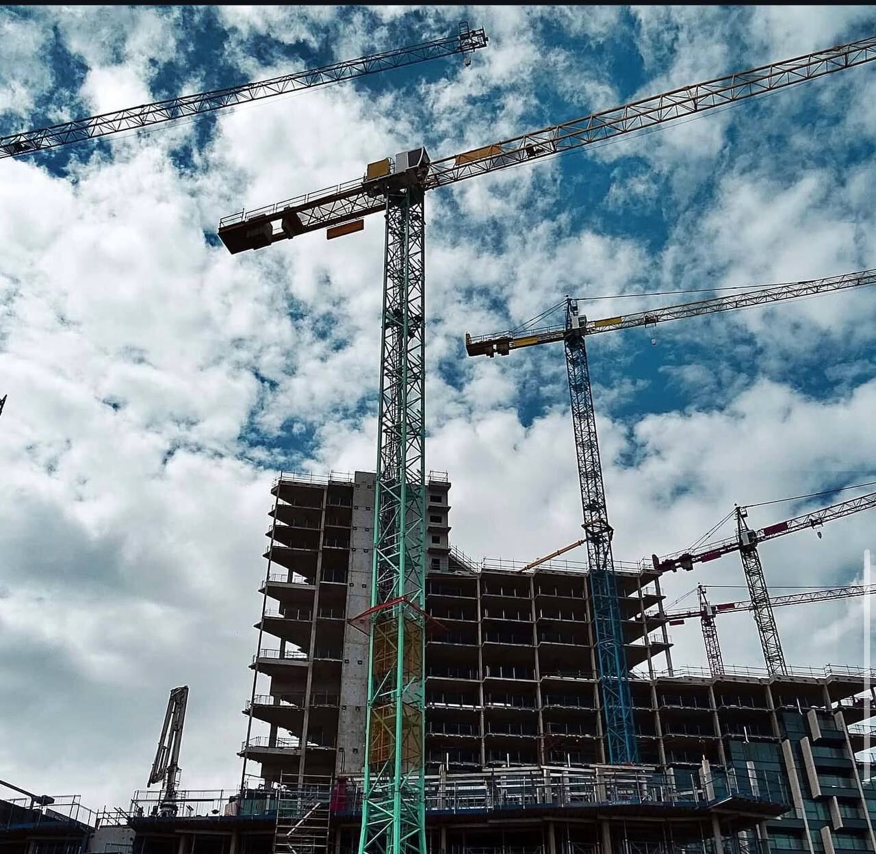 Tower cranes rising above a multi-storey concrete structure on a Deck, Steel & Concrete project