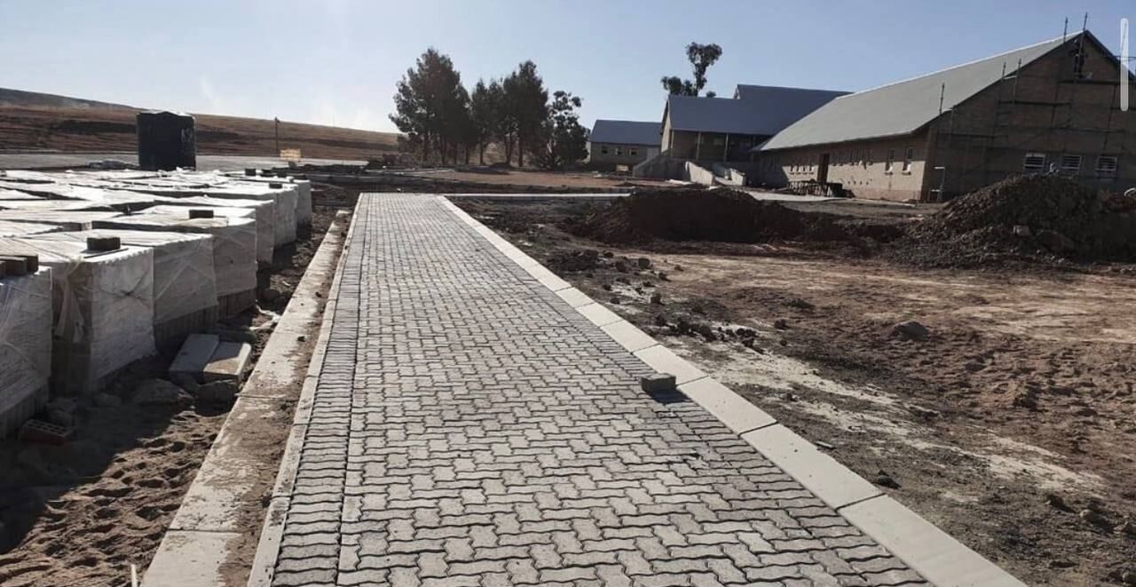 Newly laid interlocking concrete paving leading to brick buildings on an institutional site