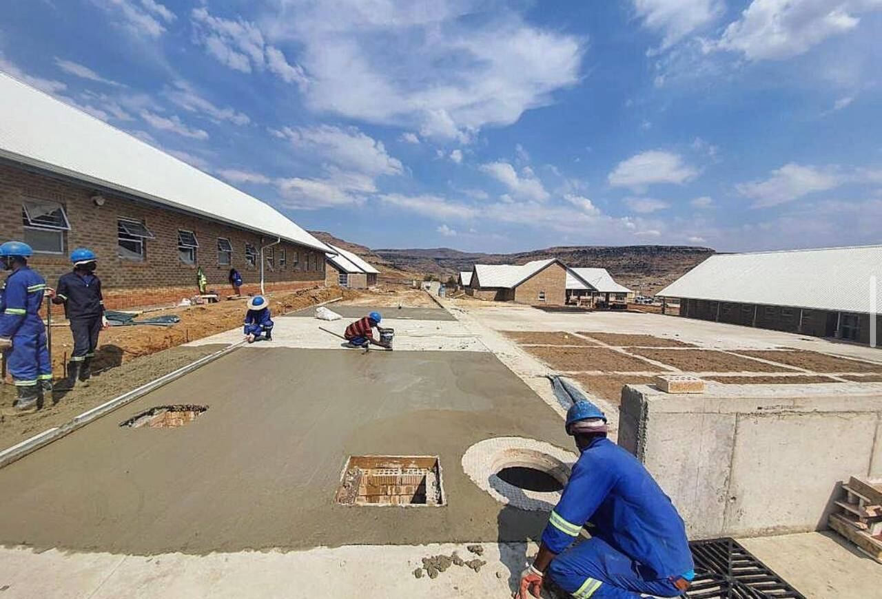 Concrete bedding slab being finished at an institutional school site with workers in PPE