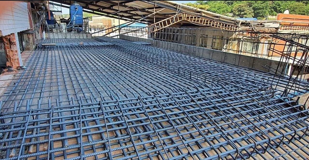 Wide rooftop reinforcing steel mesh laid out across a building under construction